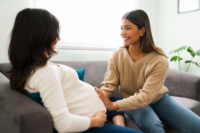 Mujer doula posparto brindando apoyo a una madre con su bebé recién nacido en casa, simbolizando cuidado, confianza y profesionalismo.